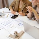 Two professionals collaborating on financial documents in a modern office setting.