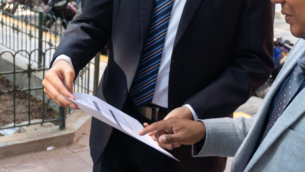 pexels-photo-37018547-37018547 Two business professionals discussing and exchanging documents outdoors in Piura, Peru.